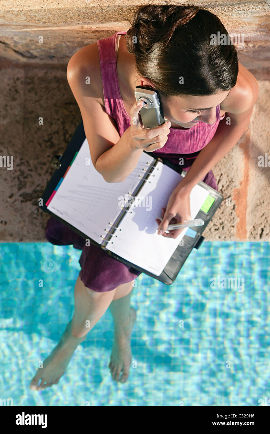 Woman by swimming pool with cellphone and organizer Stock Photo