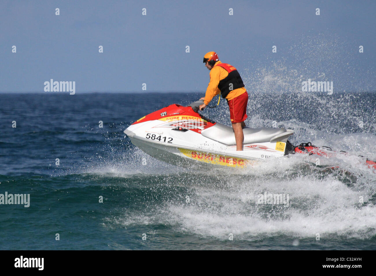 Australian surf lifesaver on a jetski patrols the beach in Australia crashing through the waves Stock Photo