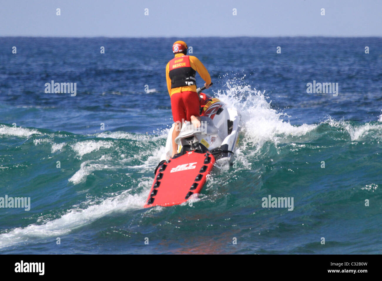 Australian surf lifesaver on a jetski patrols the beach in Australia and crashes through a wave Stock Photo