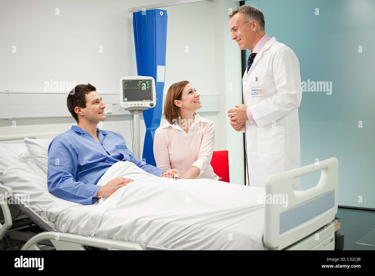 Wife visiting husband in hospital, talking to doctor Stock Photo
