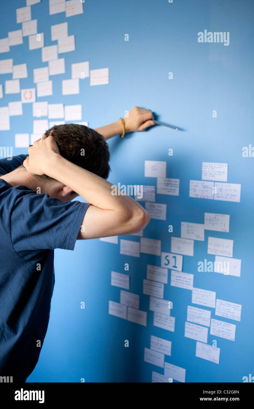 Teenage boy revising for Maths A Level with revision cards stuck on his bedroom wall. Stock Photo