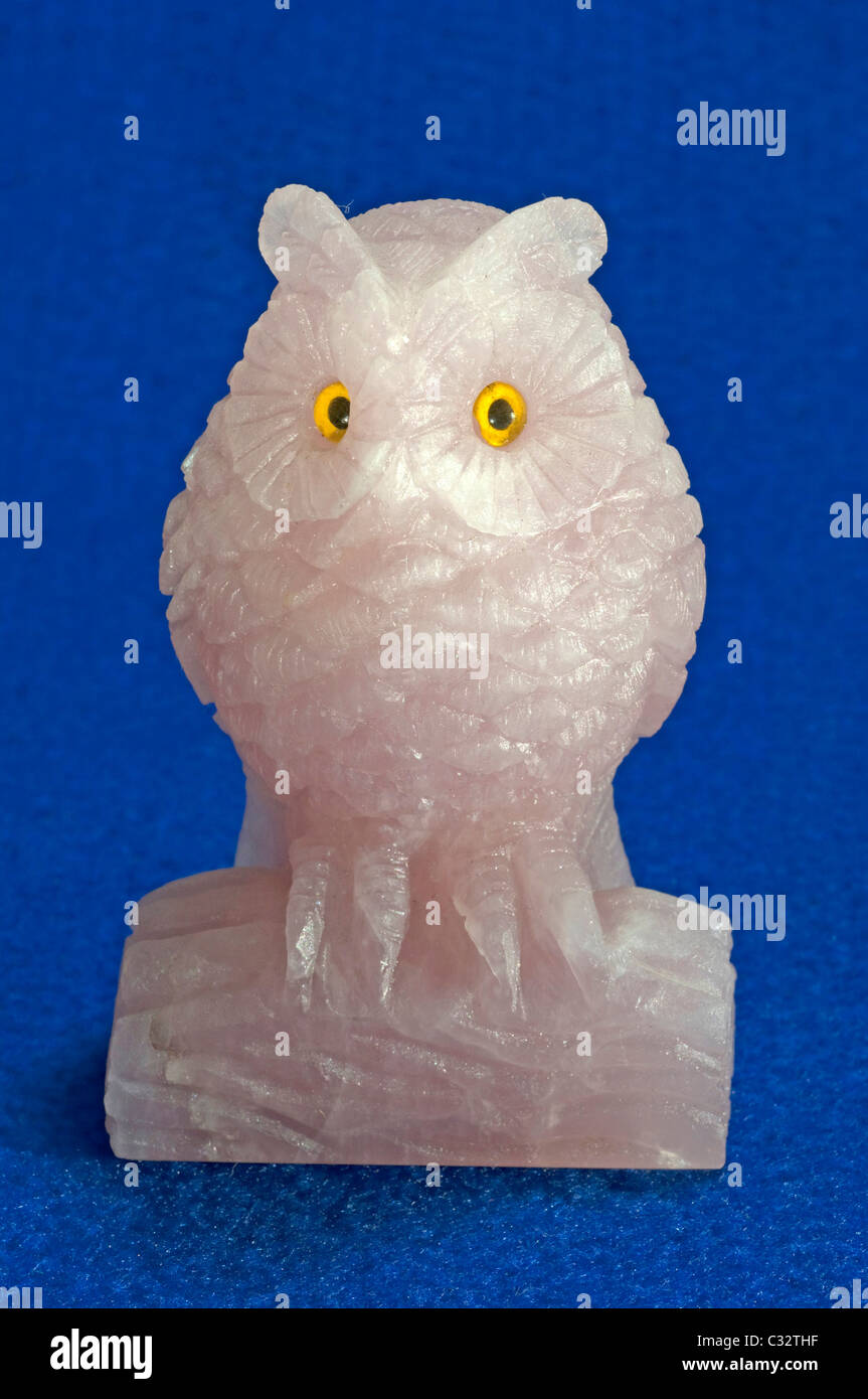 Owl made of Rose Quartz. Studio picture against a blue background. Stock Photo