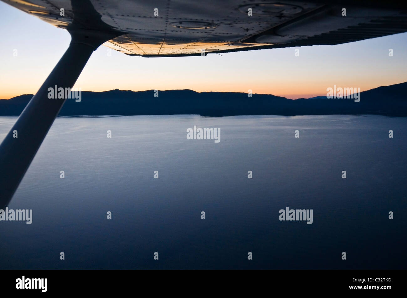 The wing of a small airplane reflects an aerial view of a sunrise over Lake Tahoe, CA. Stock Photo