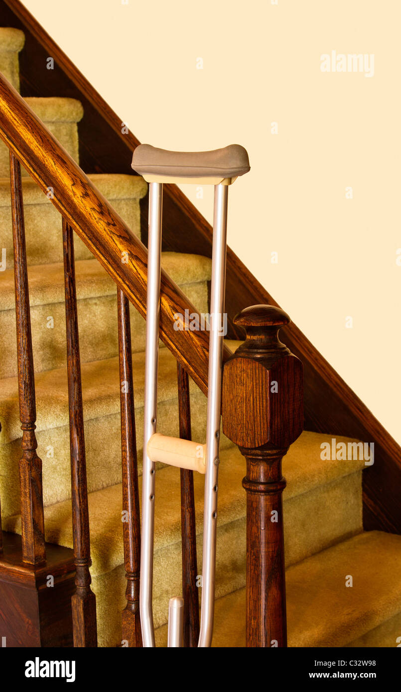 Crutch leans against railing of stairs with plain wall behind providing  copy space Stock Photo - Alamy