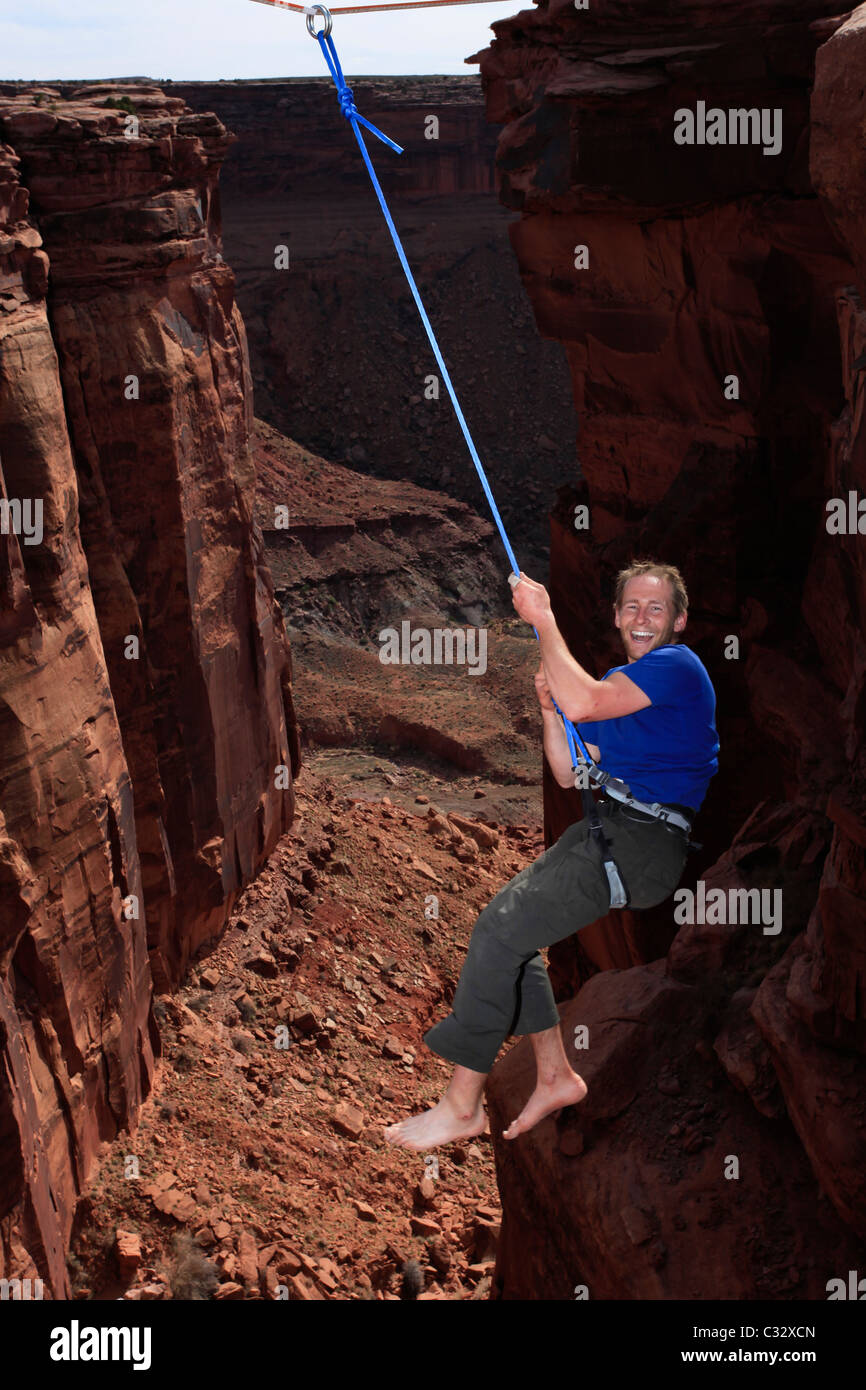 A male highliner takes a fall highlining at the Fruit Bowl in Moab