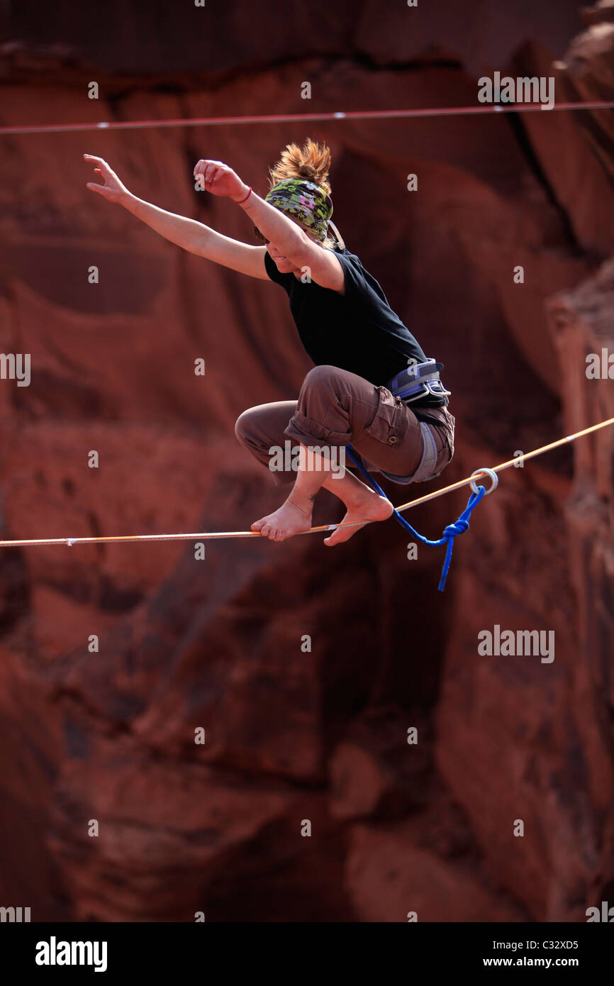 A female highliner stands up on a highline at the Fruit Bowl in Moab