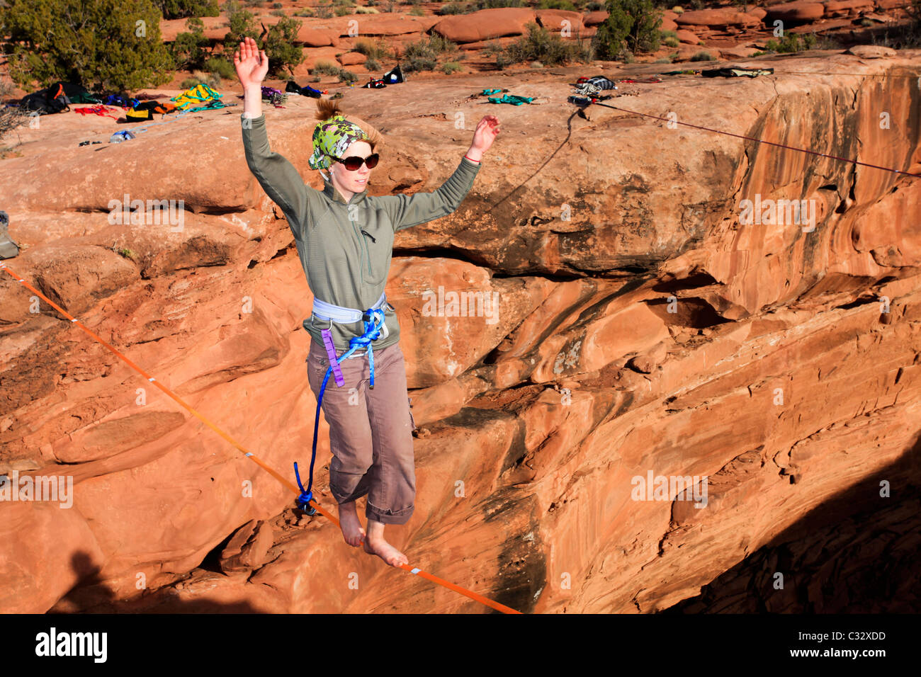 A female highliner walks across a highline at the Fruit Bowl in Moab