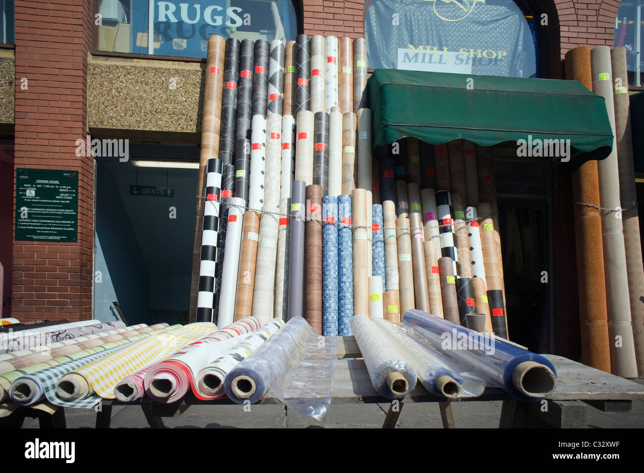 Long rolls of vinyl floor coverings displayed outside a shop front Stock Photo