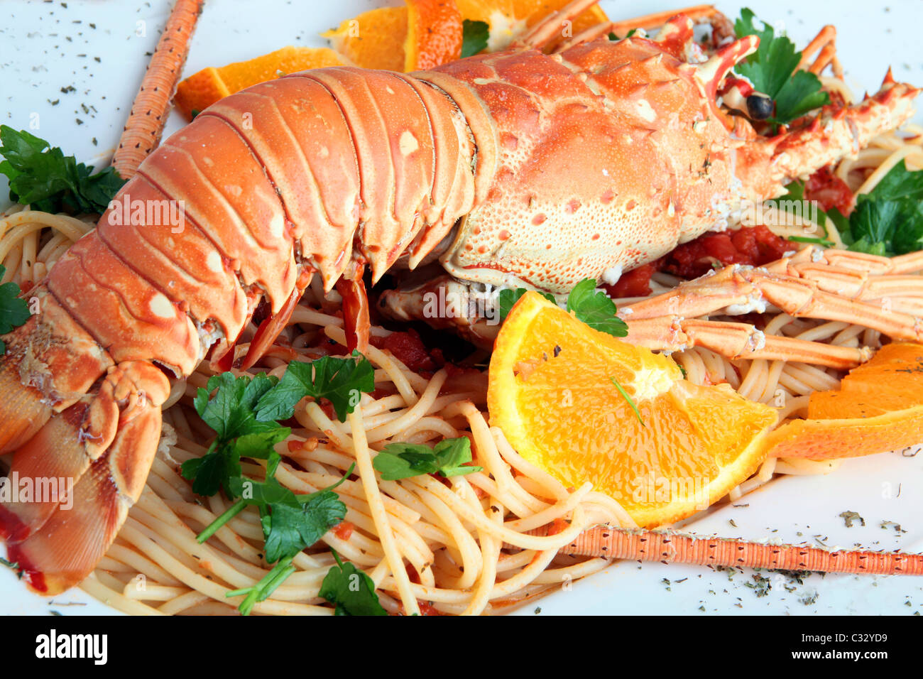 Cooked lobster on pasta decorated with slices of orange and parsley, Greece Stock Photo