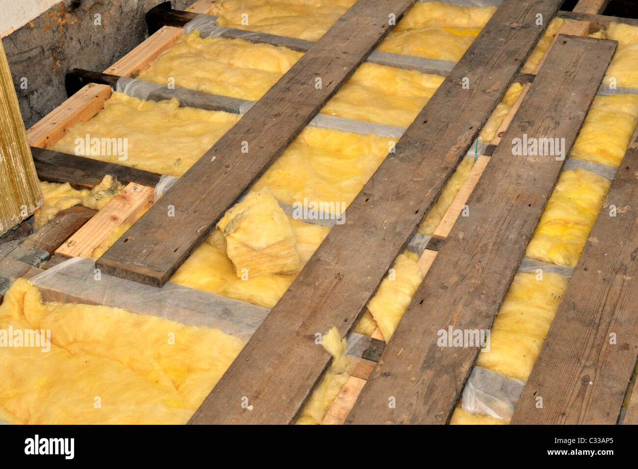 Installation Of Fibreglass Insulation Under Floorboards In An Old Suspended Timber Floor To Lessen Heat Loss Stock Photo Alamy