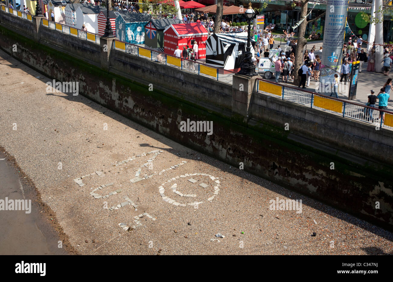 No Cuts spelt out on River Thames shore in front of Royal Festival Hall, London Stock Photo