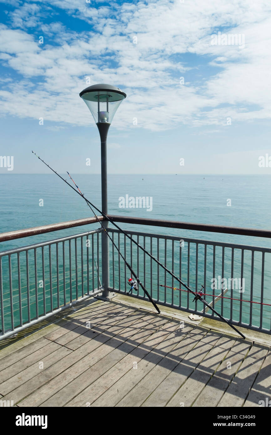 End of pier ocean view with two fishing rods / fishing poles resting  against railings waiting for a bite Stock Photo - Alamy