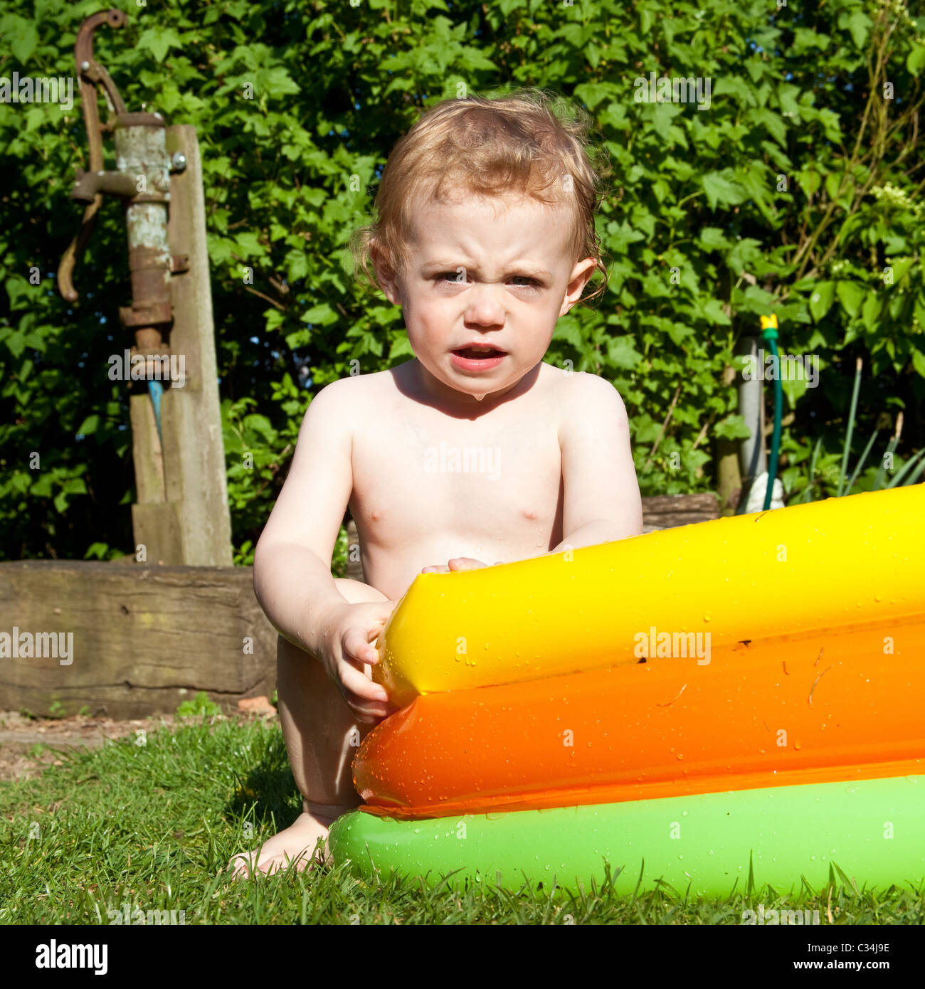 Boy (2 years old) playing in a paddling pool, Hampshire, England Stock