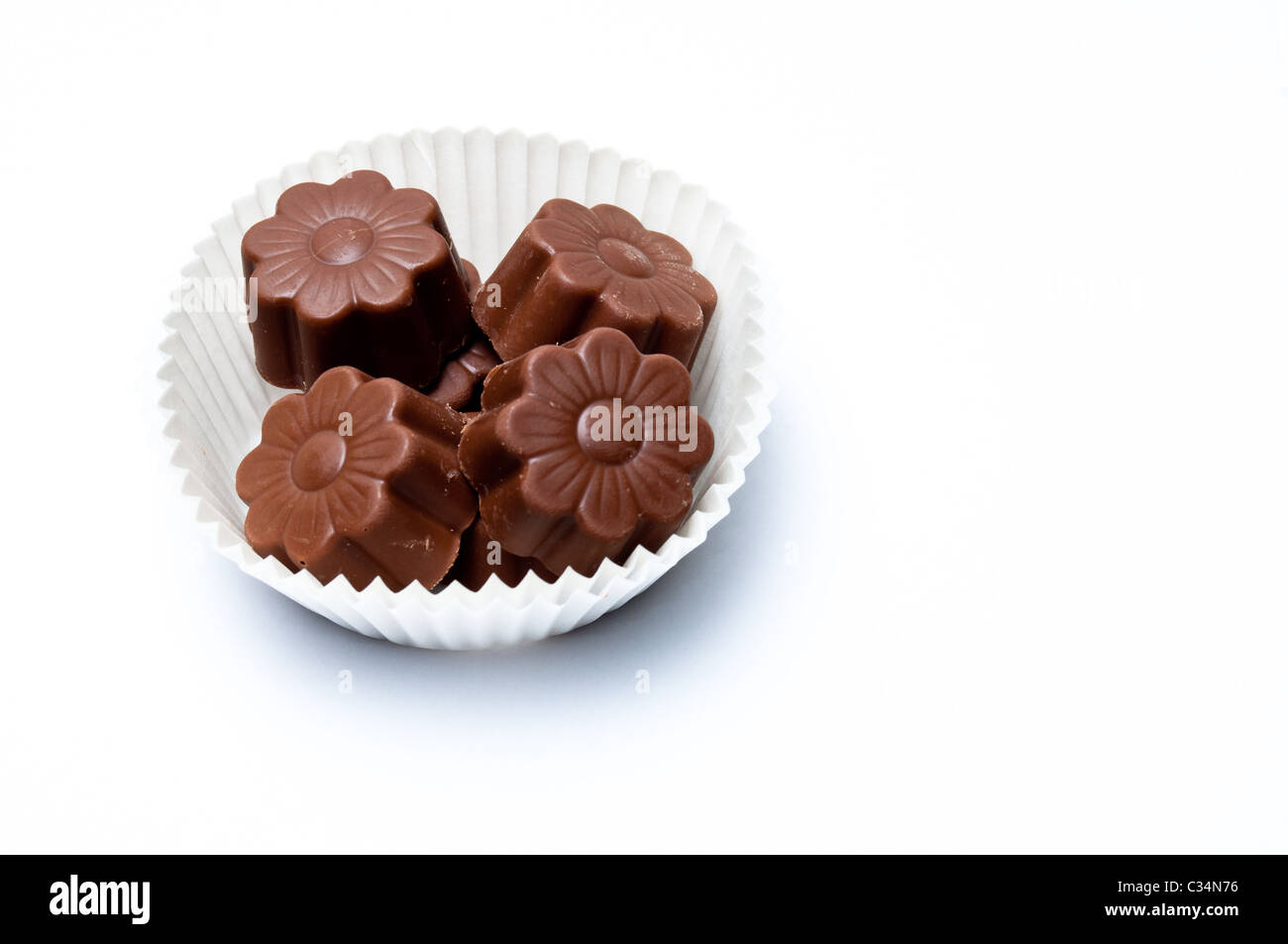 Daisy shaped chocolate assortments in a paper basket isolated on white