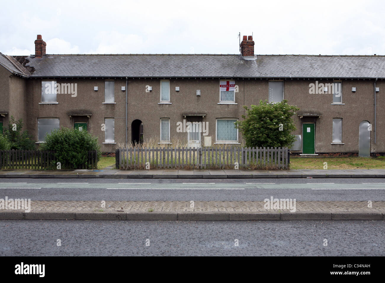 An occupied house displaying the flag of St. George amongst boarded up derelict houses, Grangetown, Middlesbrough, England, UK. Stock Photo