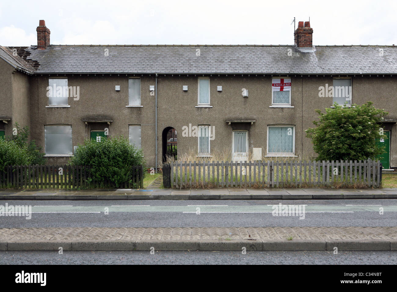 An occupied house displaying the flag of St. George amongst boarded up derelict houses, Grangetown, Middlesbrough, England, UK. Stock Photo