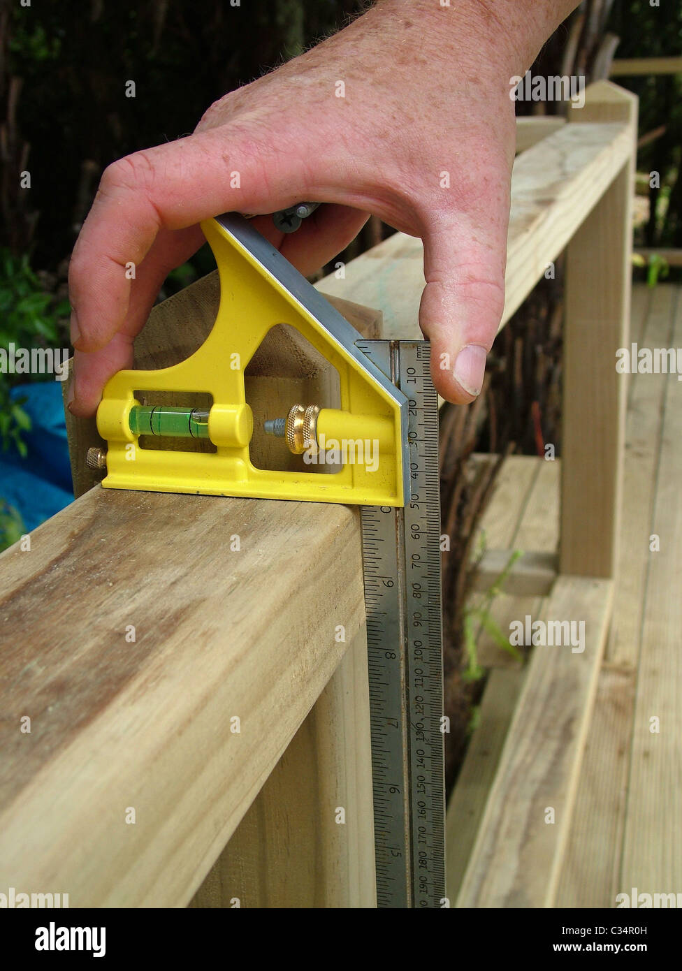 Measuring timber for plumb carpentry work while building a deck Stock