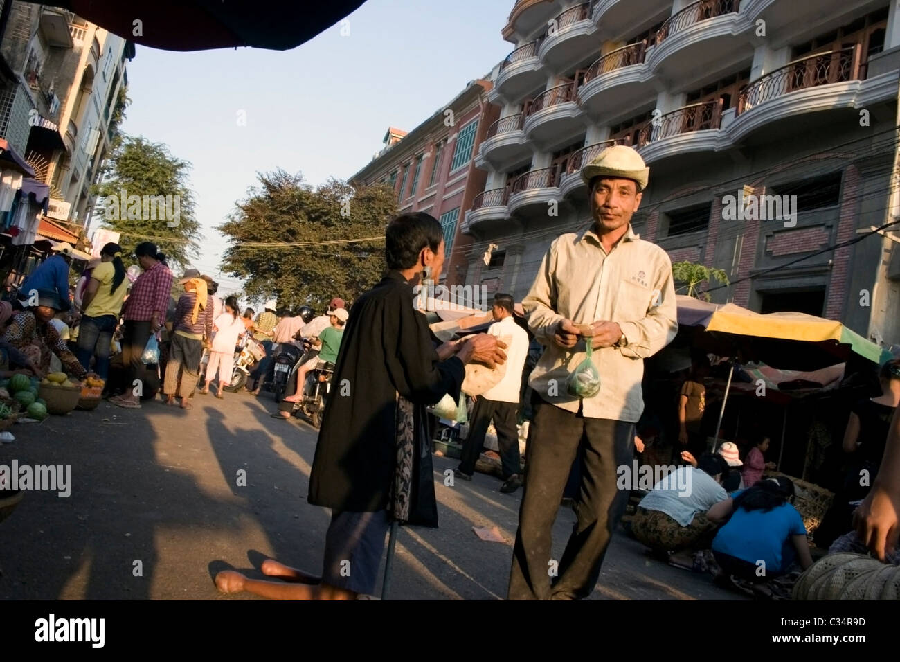 An Asian man is walking past a handicapped amputee man who is begging for money in Phnom Penh, Cambodia. Stock Photo