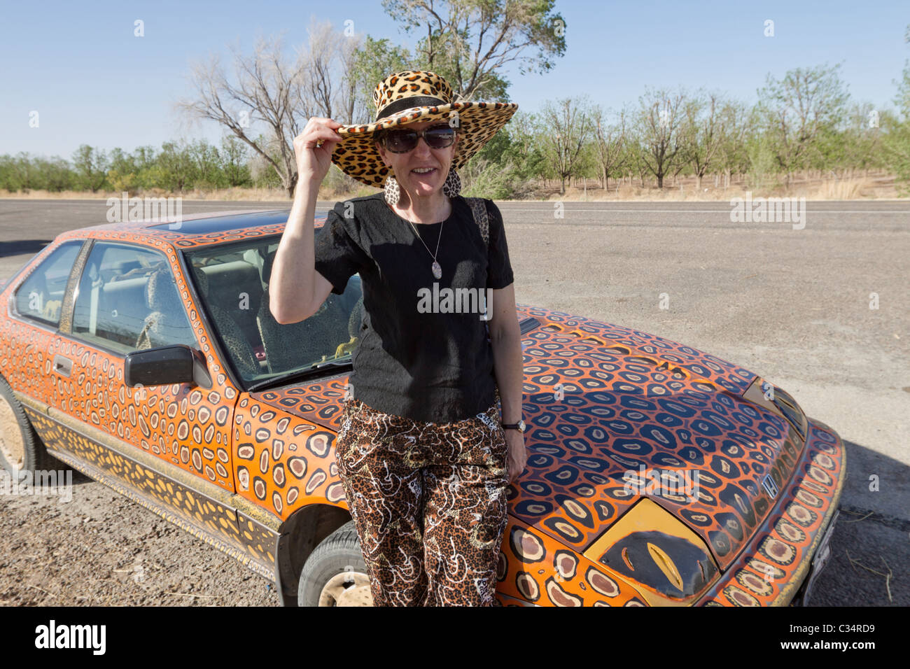 Woman sitting her hand-painted car, with matching hat, in West Texas. Stock Photo