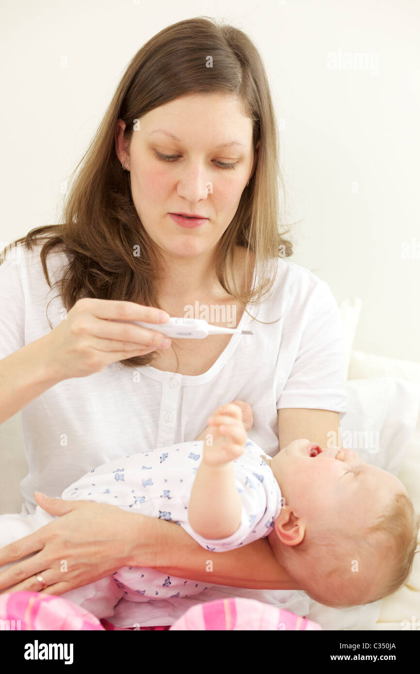Crying baby having her body temperature taken with digital thermometer