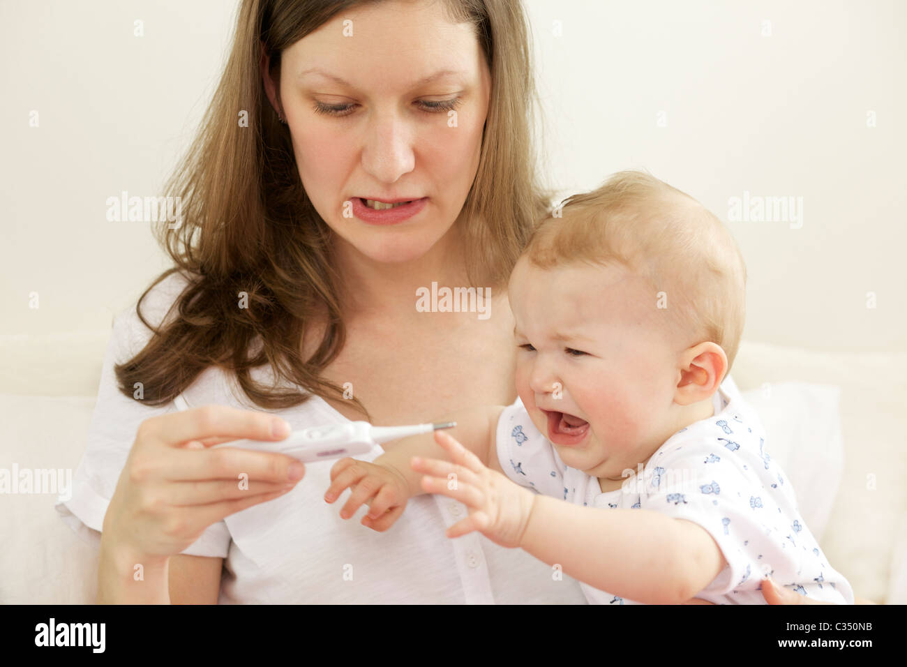 Crying baby having her body temperature taken with digital thermometer