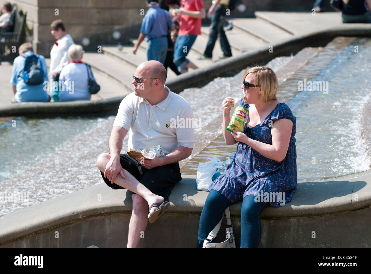 Couple sitting by fountain in Victoria Square, Birmingham Stock Photo
