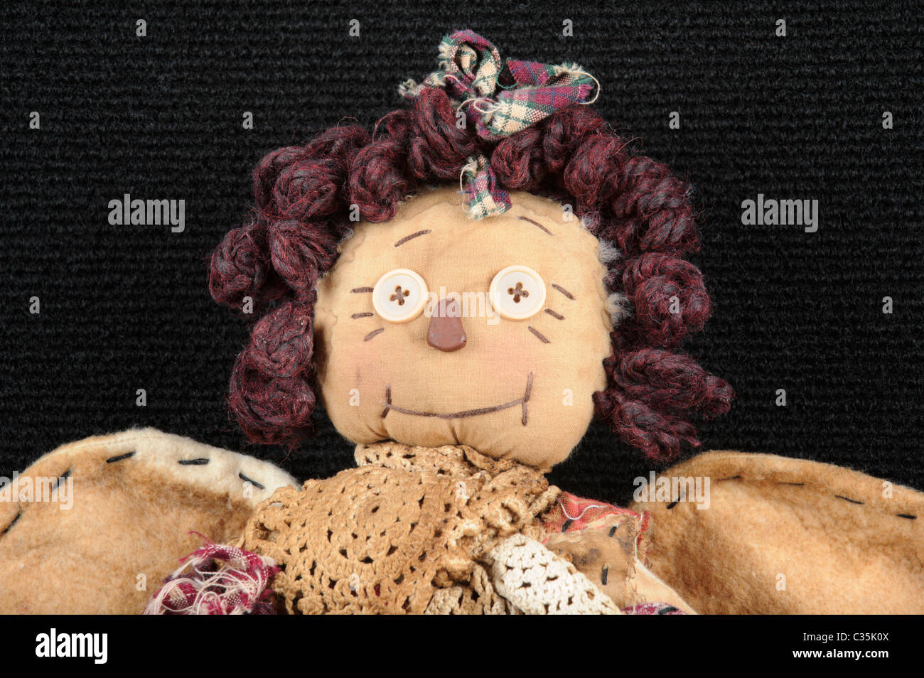 Rag doll in close up of face with buttons for eyes and yarn hair, handmade children's toy in a