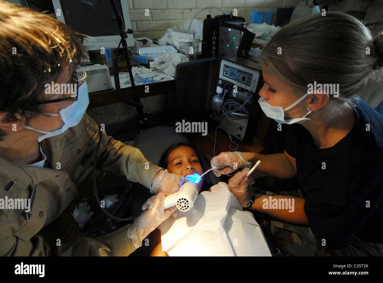 Dentist performs dental care for child at the Monsignor Romero Roman Catholic School in Valley of Peace, Belize. Stock Photo