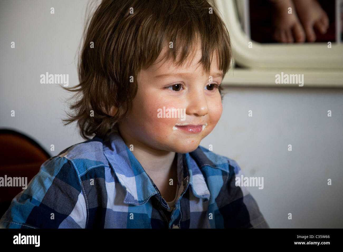 2 year old boy sat in high chair at table watching cartoons Stock Photo