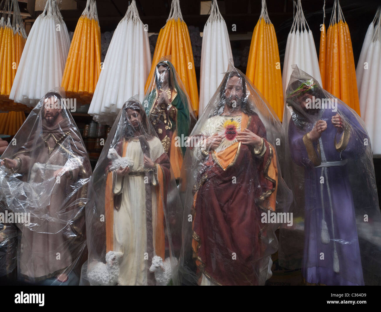 Small religious Catholic statues stand for sale covered in clear