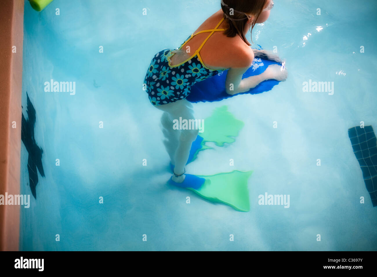 Girl holding a kickboard training for a swim race in the lap pool Stock