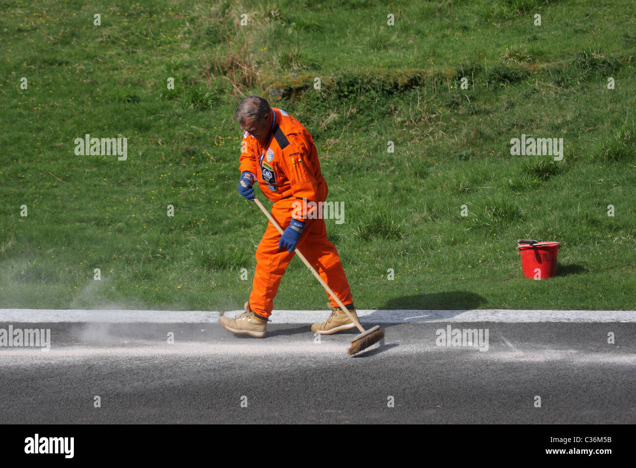 A track marshal cleaning the track surface after an oil spillage, at Loton park hillclimb, Shropshire, UK. Stock Photo