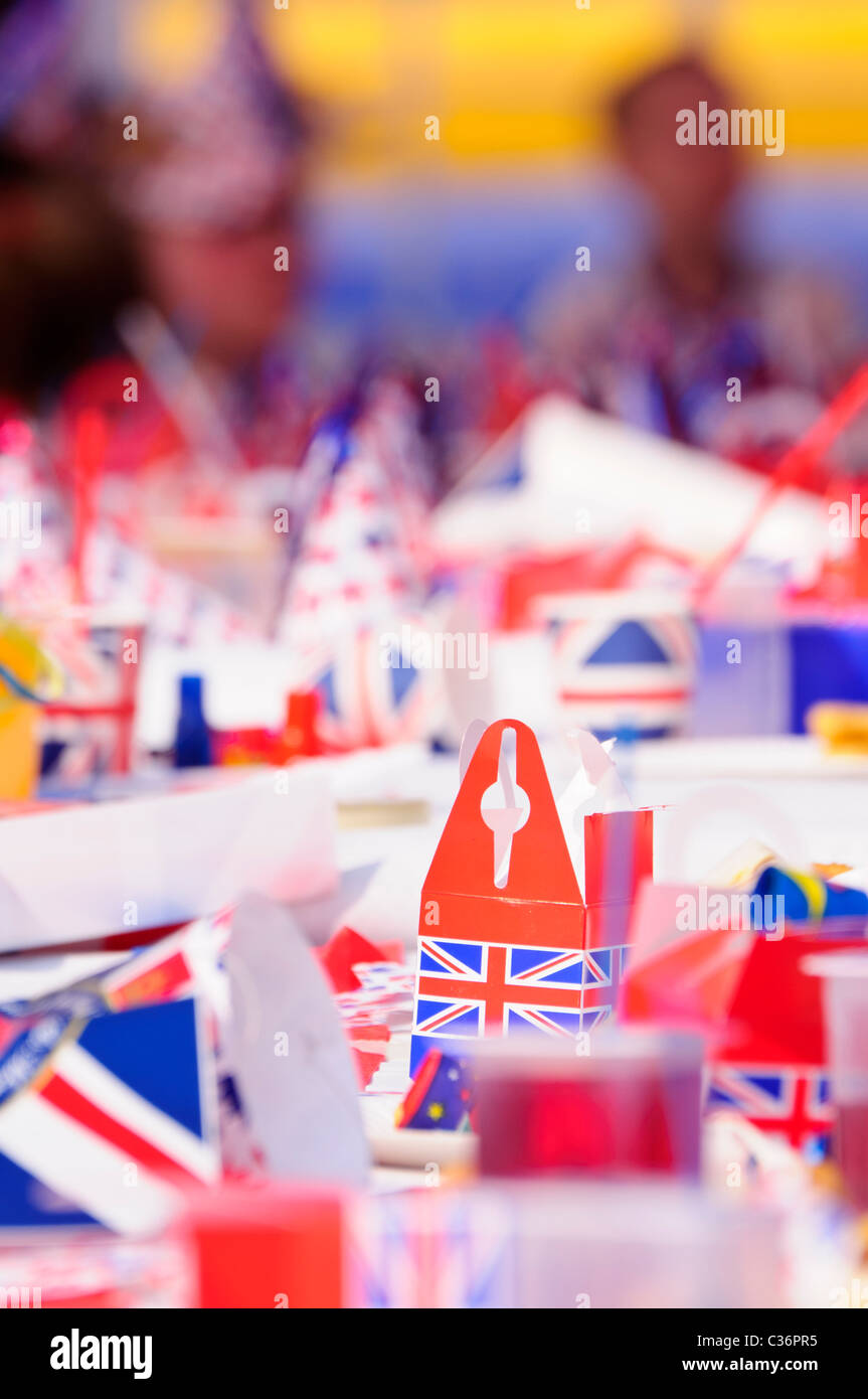 Children sit at long tables with red, white and blue party accessories at a Royal event street party Stock Photo