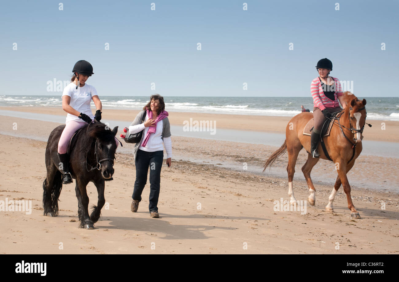 Girls riding their horses on Holkham beach, North Norfolk, UK Stock