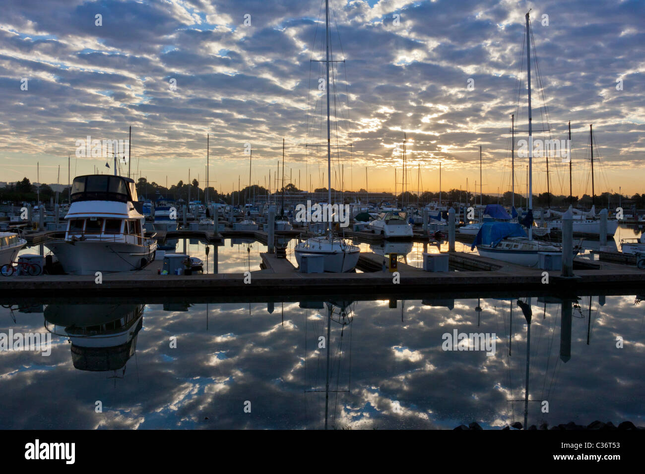Clouds and boats reflected in marina at sunrise Stock Photo - Alamy