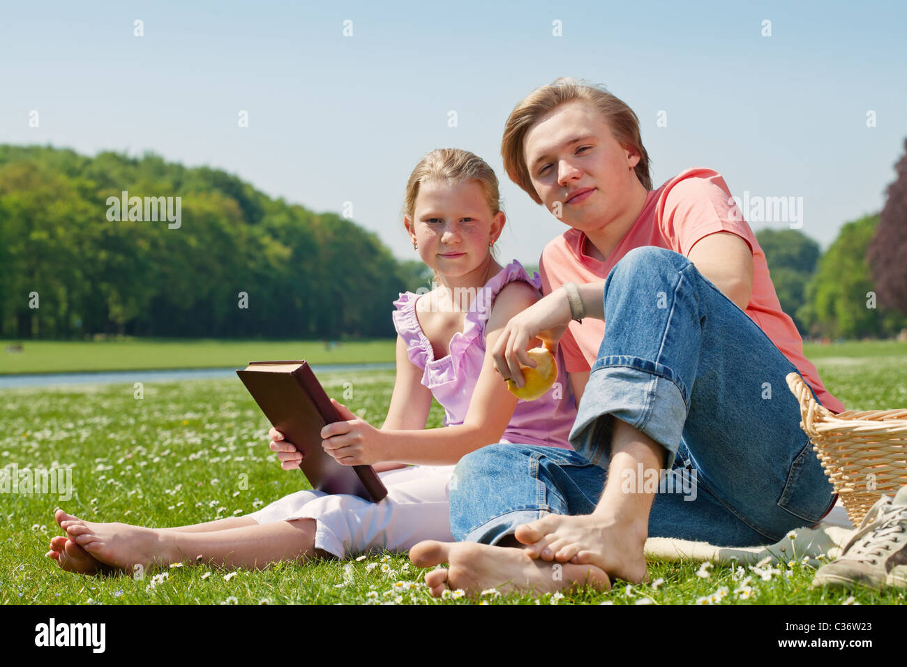 Teenager brother and sister having a picnic in the park in a bright ...