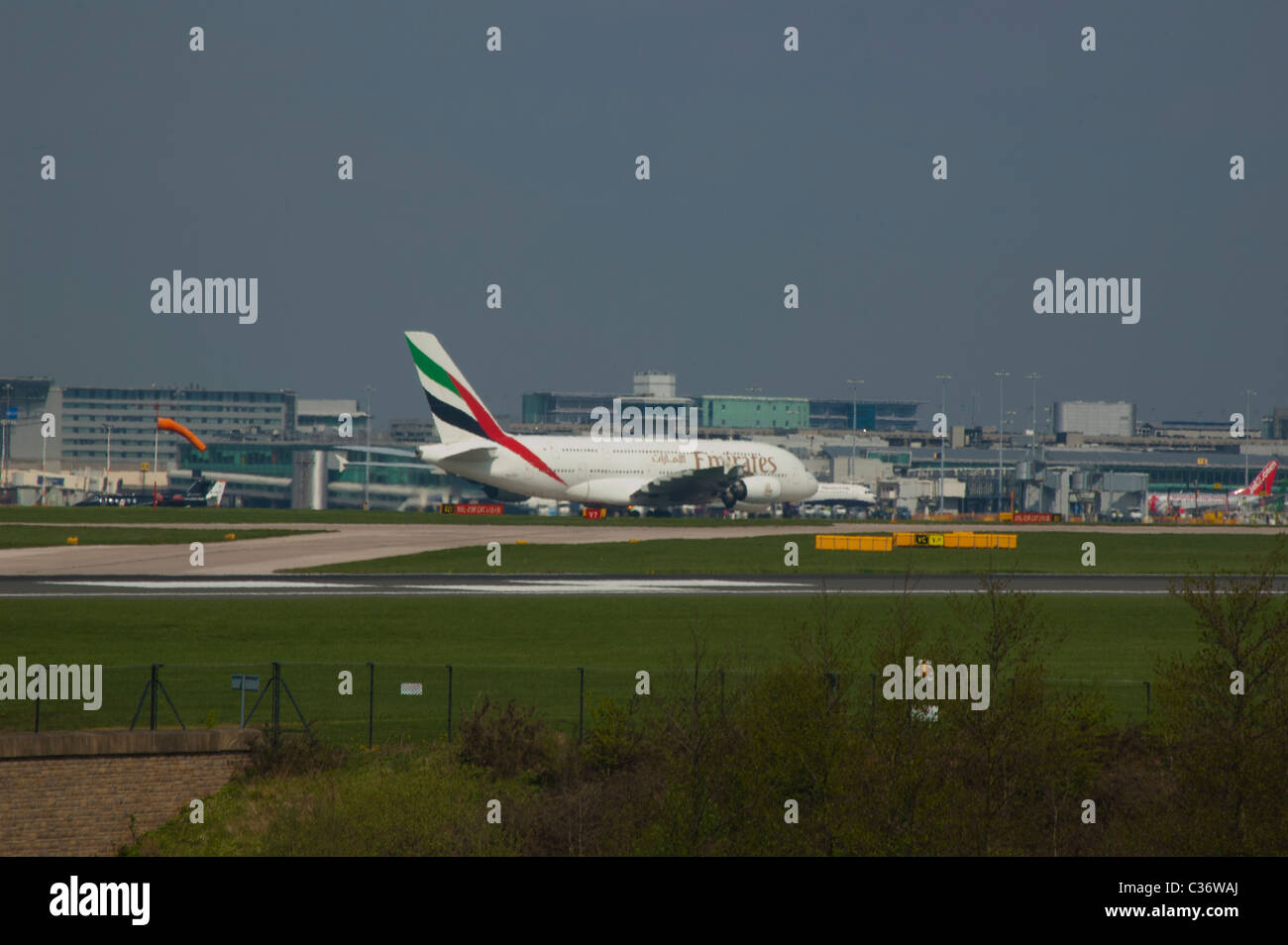 Airbus A380 on the apron at Manchester Airport as passengers disembark. Its size can easily be seen against the terminal behind Stock Photo