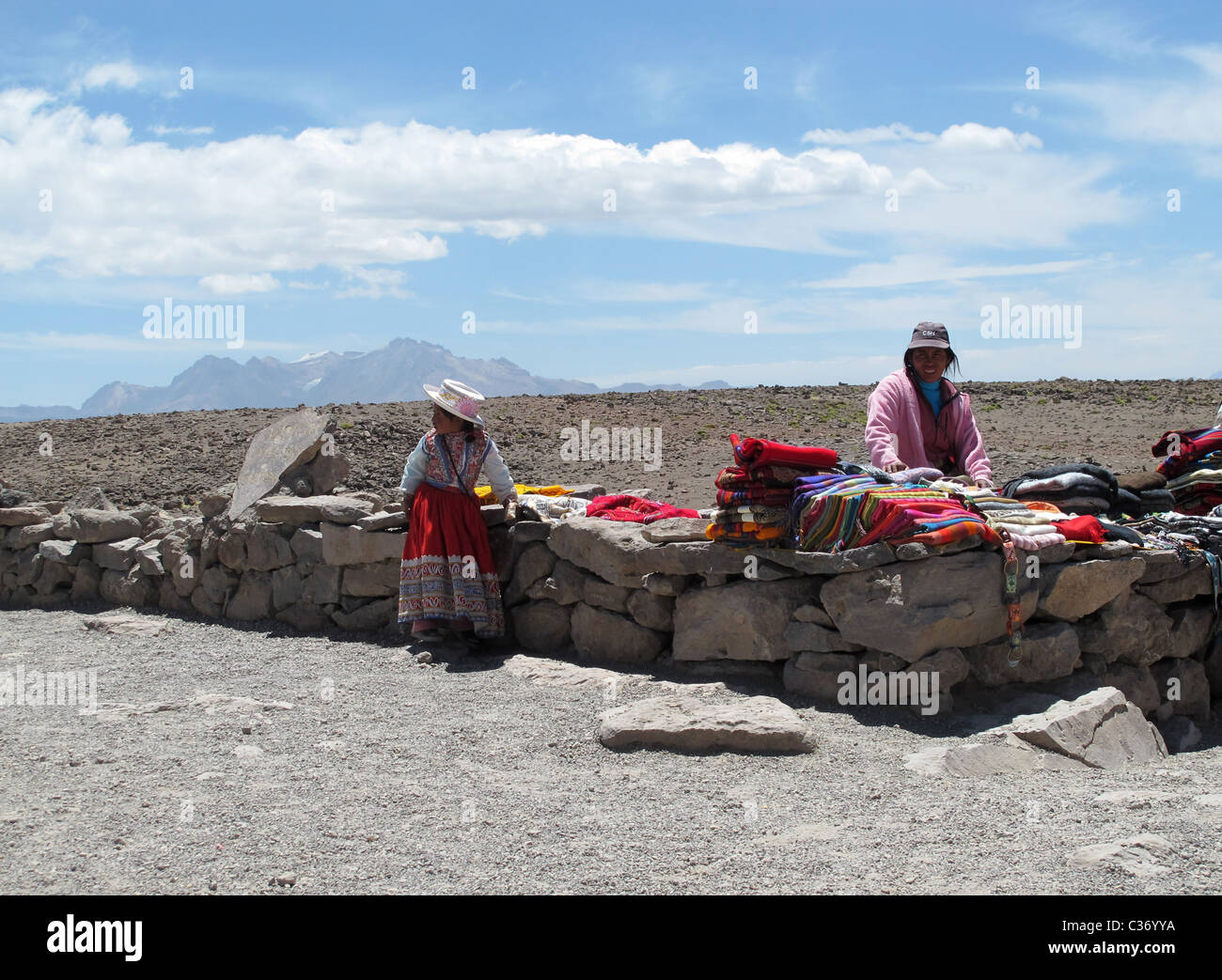 Cordillera volcanica en los Andes Centrales with Quechua woman selling textiles, Peru Stock Photo