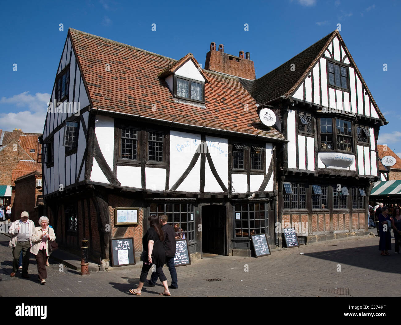 People walking past a Tudor timber fronted restaurant on The Shambles near Newgate Market, York city centre, North Yorkshire, UK Stock Photo