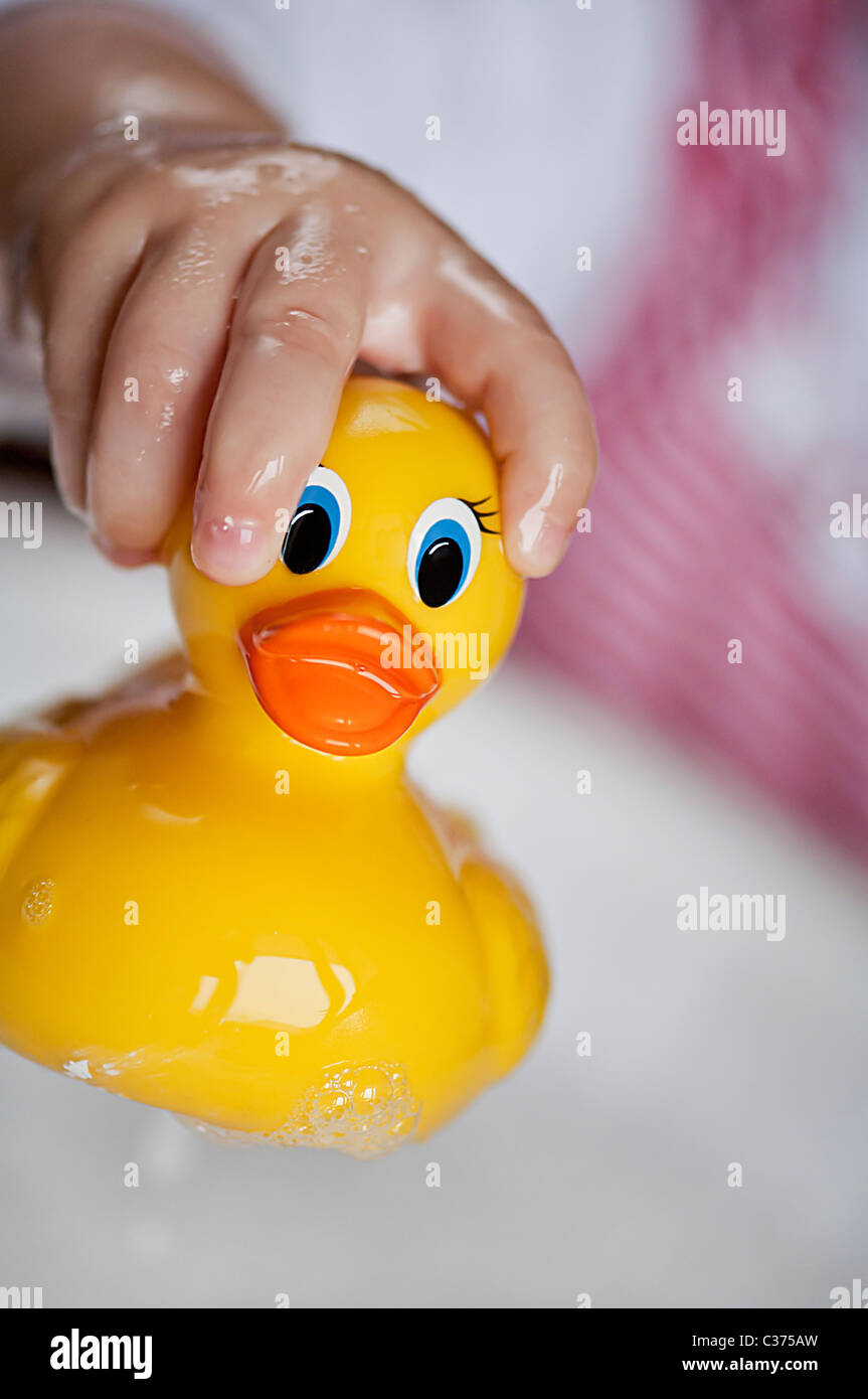 Toddler playing with a rubber ducky in a bath full of water and bubbles