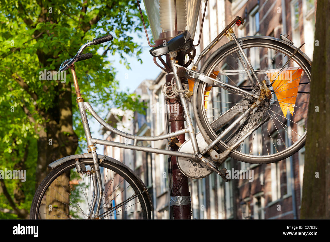 A bicycle left high on a lamp-post in Amsterdam. It's not abandoned just put there for safety: it's firmly locked to the post. Stock Photo