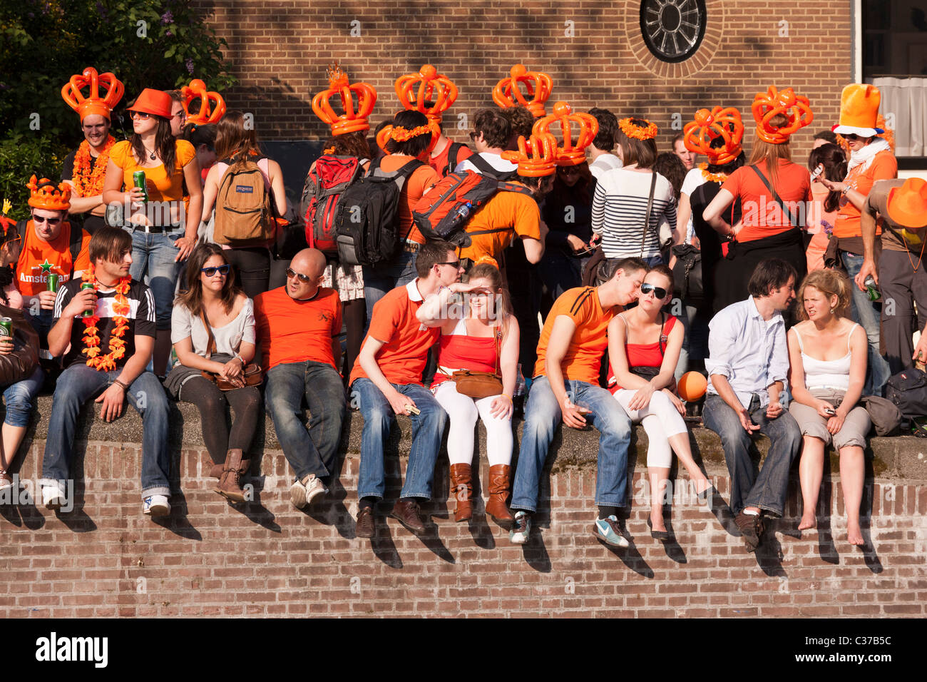 Queensday, the Queen's birthday in Amsterdam. Visitors, dressed up in orange, watching the Canal Parade in the Prinsengracht. Stock Photo