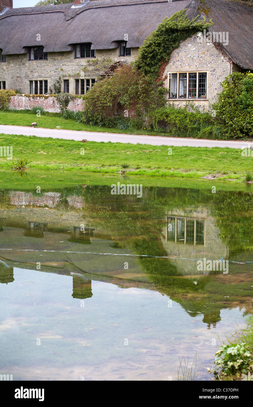 Thatched cottages at Ashmore, Dorset with reflections in pond in April
