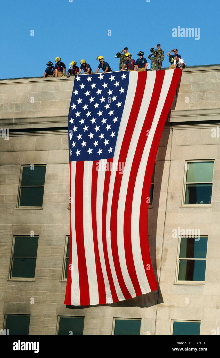 Military members rendered honors as fire and rescue workers unfurled a huge American flag over the side of the Pentagon during r Stock Photo