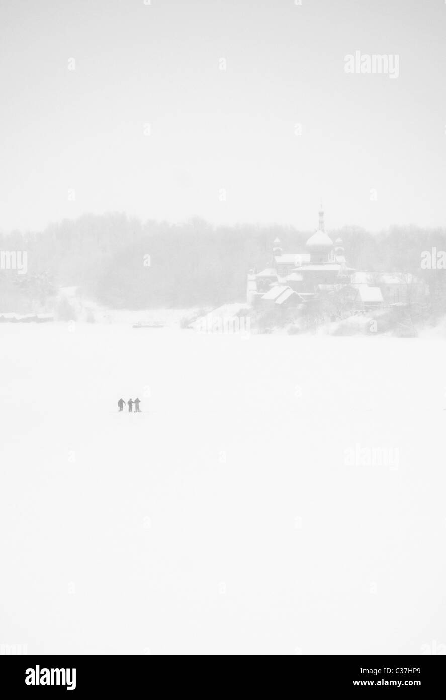 Fishermen on the frozen Volkhov River with Nikolsky monastery in the background, Staraya Ladoga, Leningrad Region, Russia Stock Photo