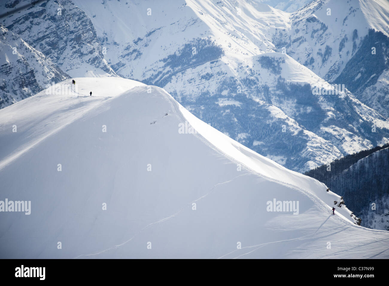 A group of skiers and snowboarders walking along a snowy ridge in Argentera, Italy. Stock Photo
