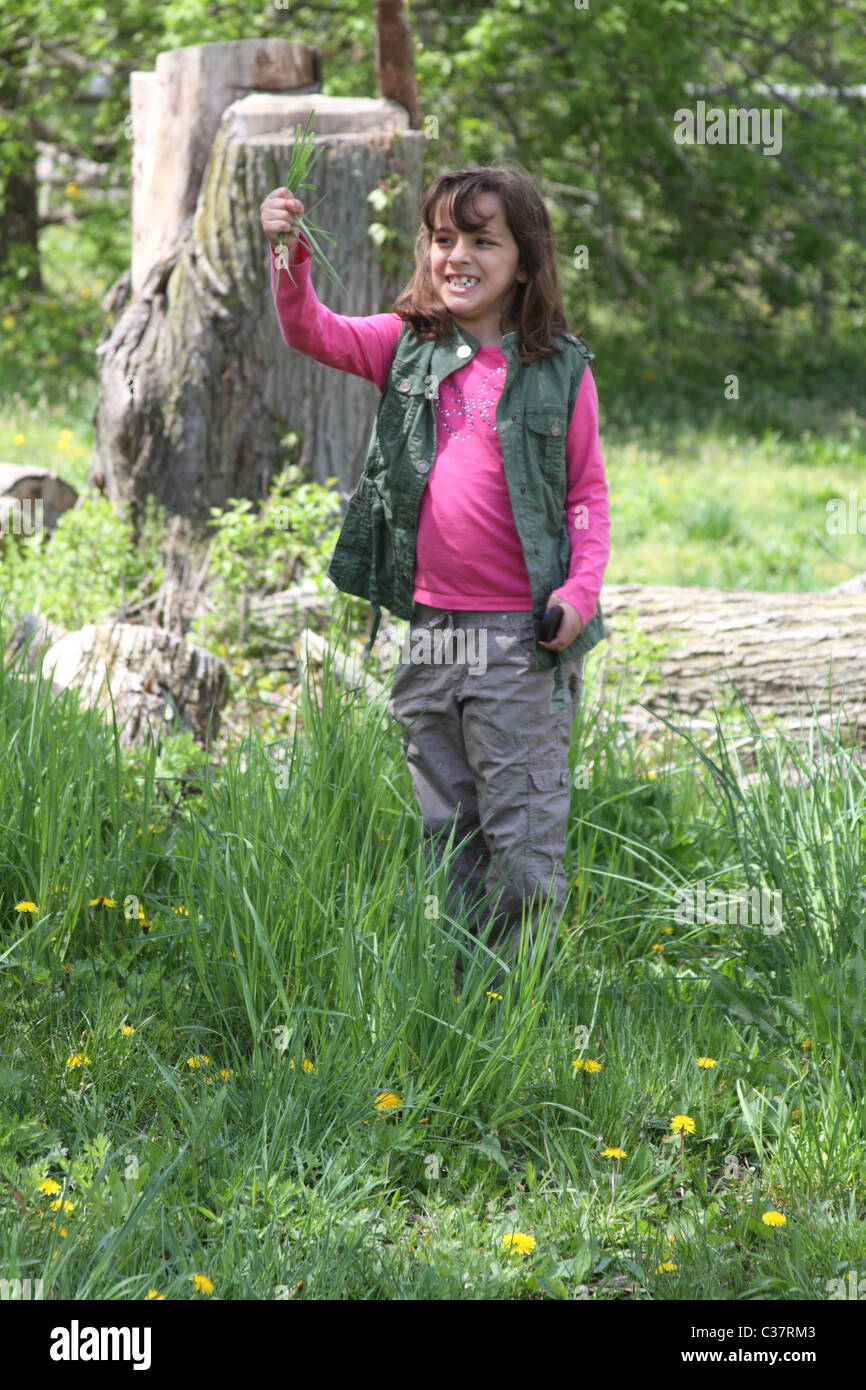 Young girl playing with the grass at a park and smiling Stock Photo - Alamy