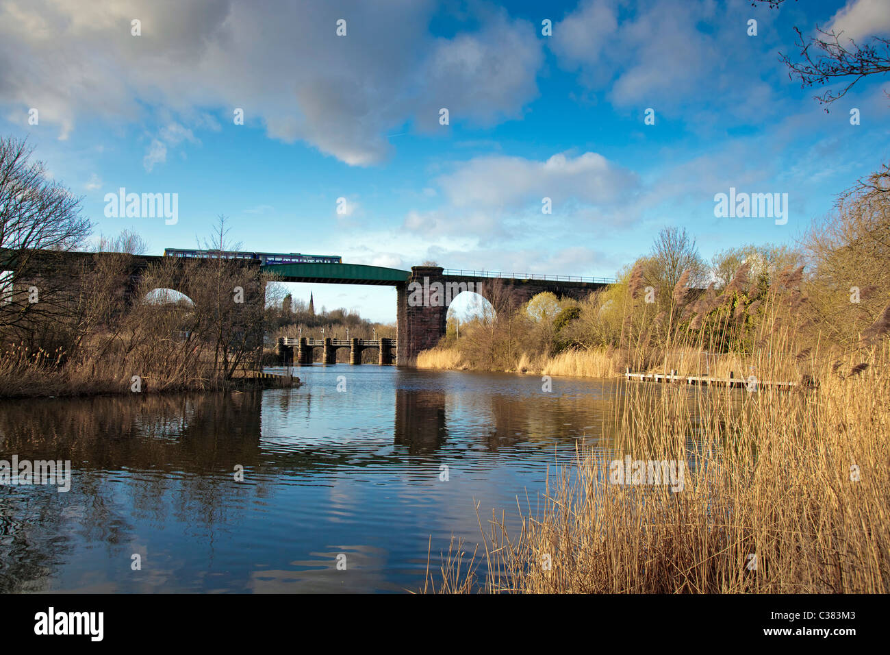 Northern Rail DMU train crosses viaduct over the River Weaver at Northwich, Hunts Locks. Stock Photo