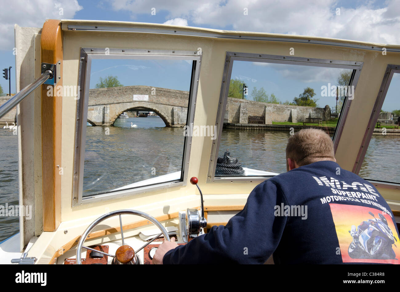 Pilot steering a boat under Potter Heigham Bridge on the Norfolk Broads