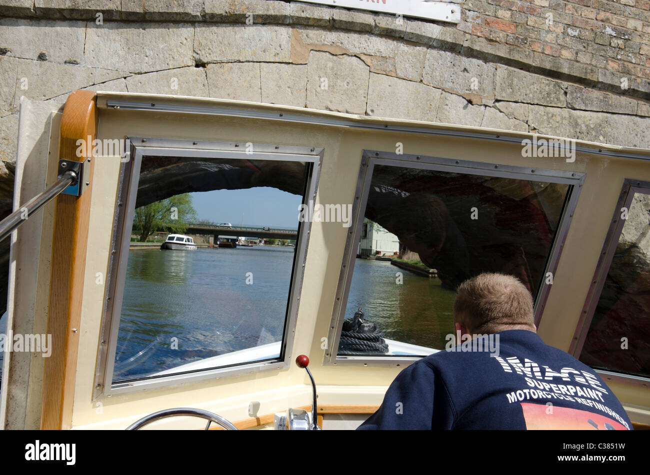 Pilot steering a boat under Potter Heigham Bridge on the Norfolk Broads